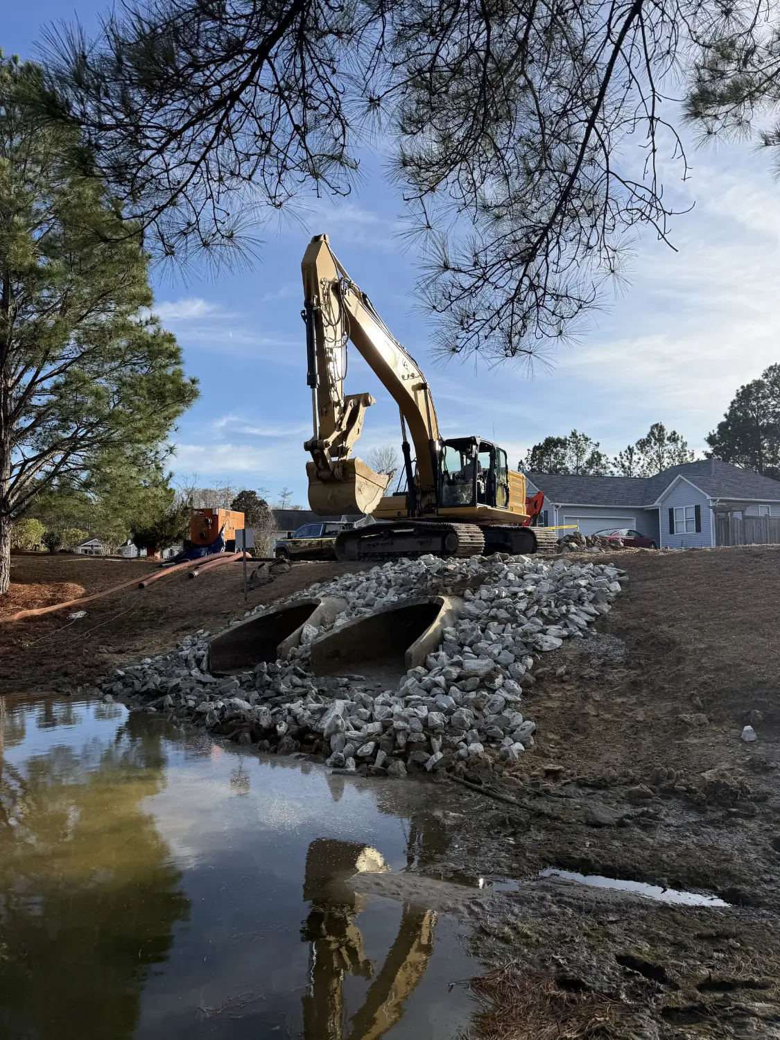Excavation of a retention pond and bioswale to manage stormwater and improve site drainage.